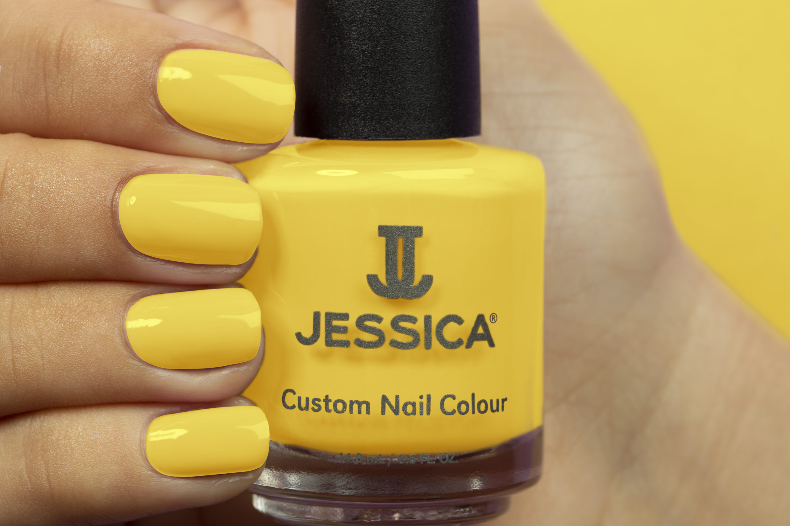 Manicured hands wearing and holding Yellow Custom Colour Nail Polish