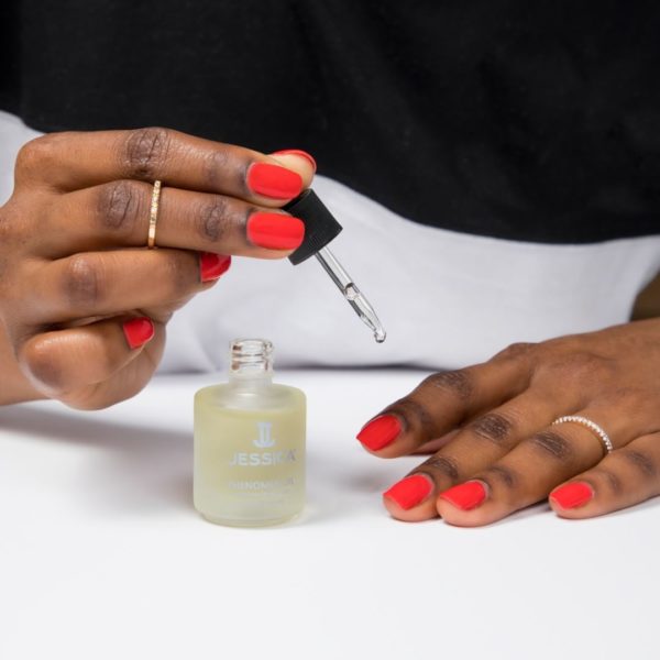 Hand applying Phenomen Oil onto the other hand's cuticles and nails